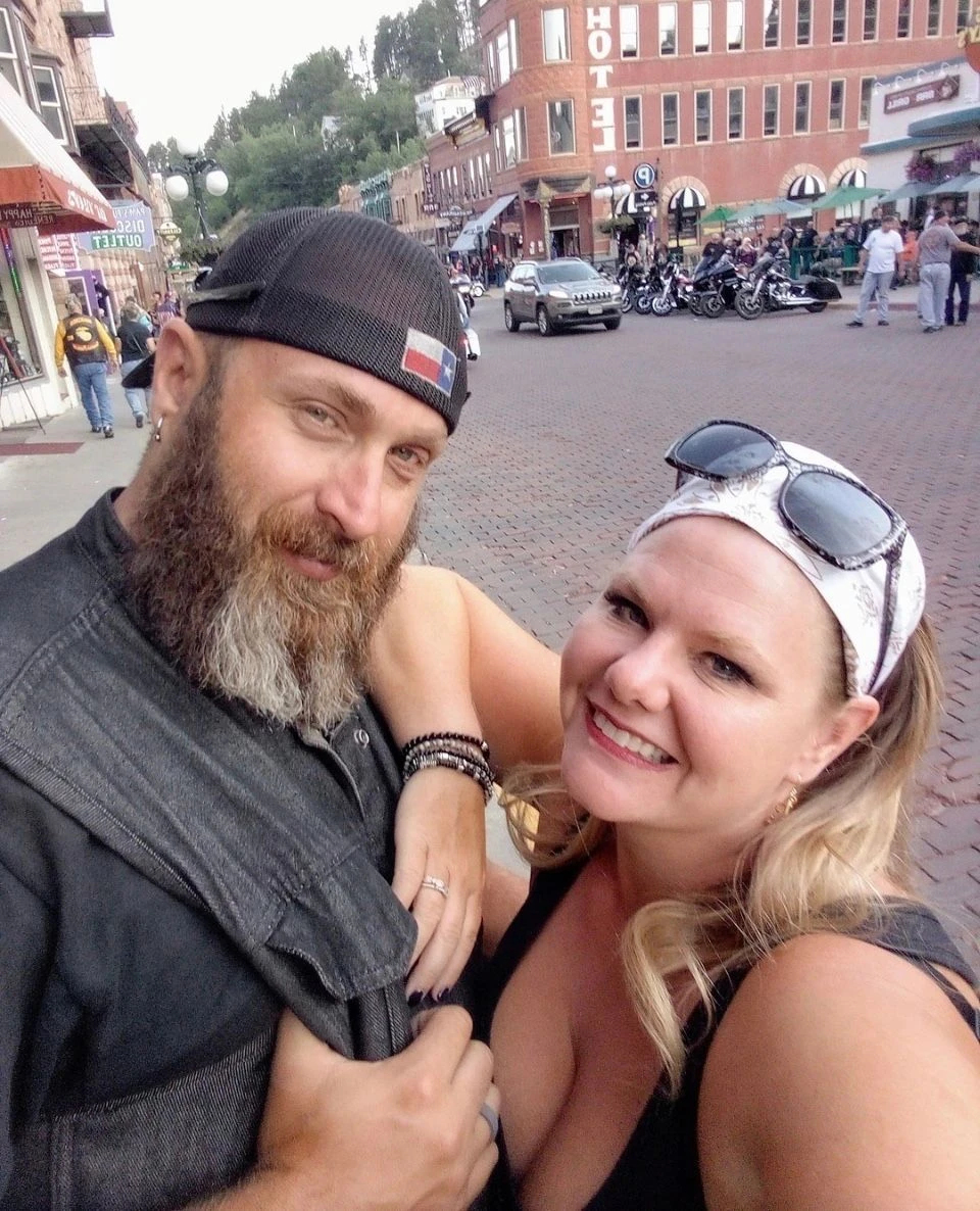 Drew and Crystal together on a Deadwood street on their wedding day, with motorcycles and historic buildings behind them.