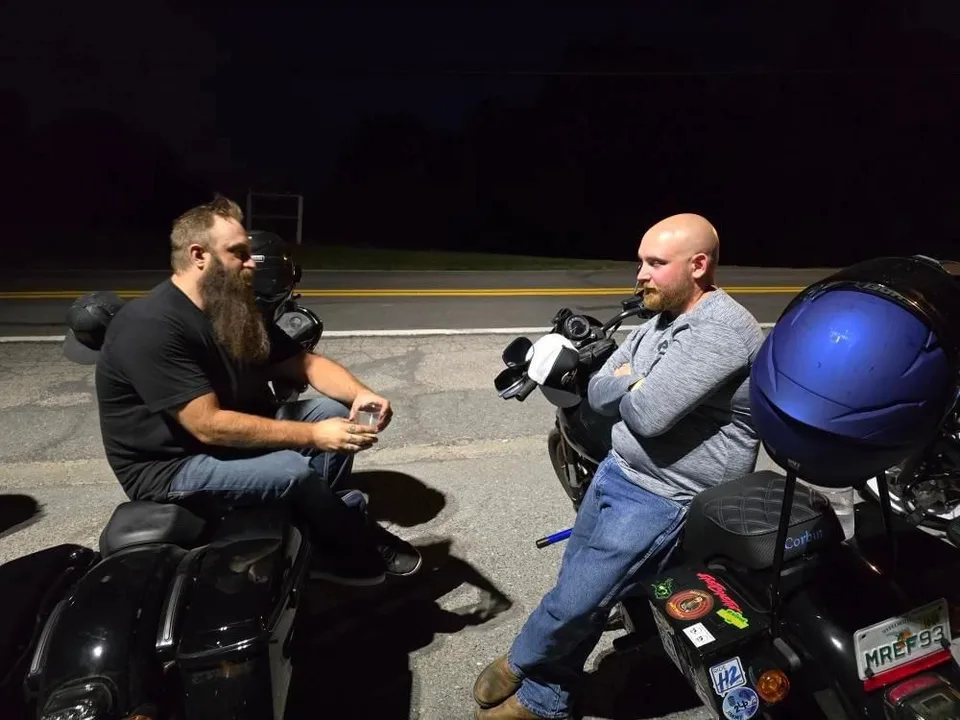 Two people talking beside motorcycles at night