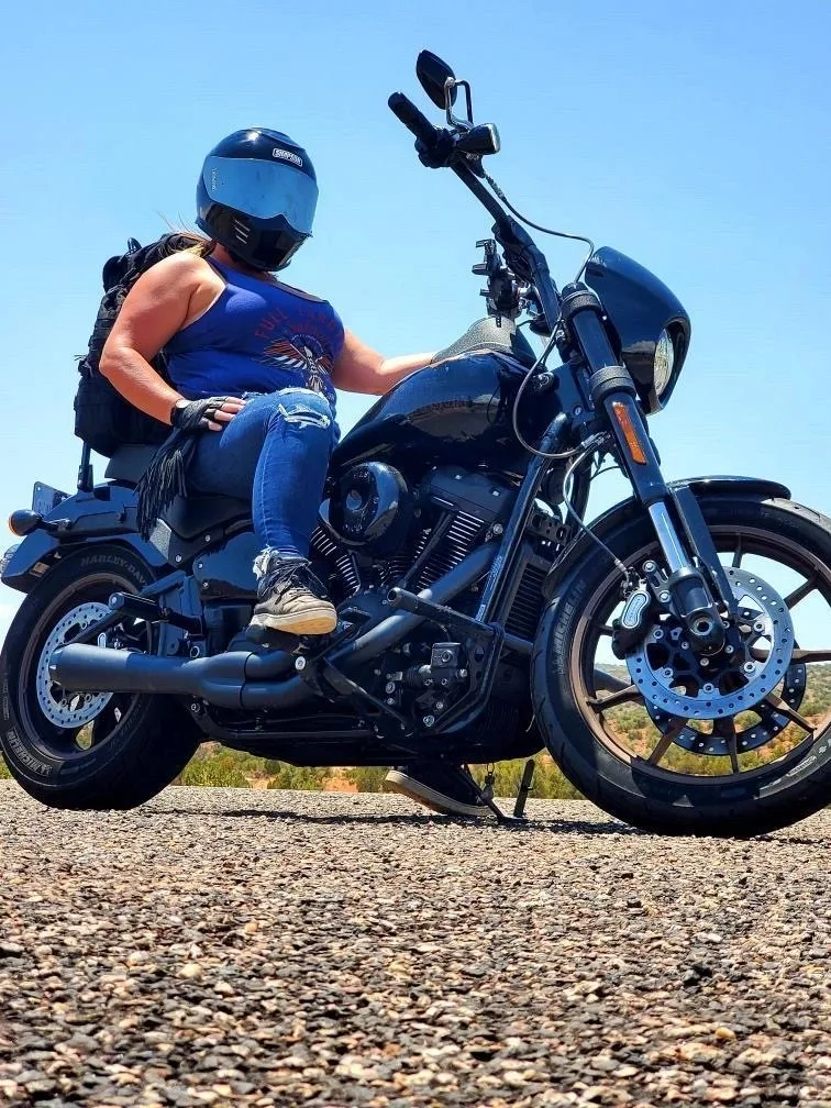 A helmeted rider seated on a motorcycle under a blue sky