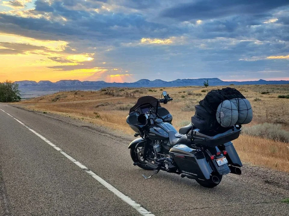 A loaded touring motorcycle beside a western landscape at sunset