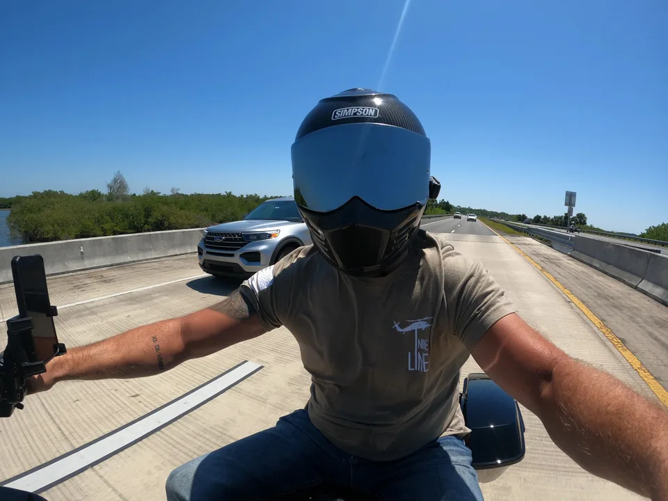 A helmeted motorcyclist riding under a blue sky