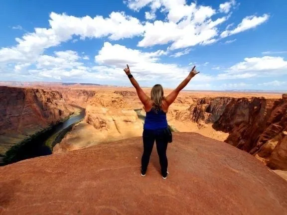 A rider with arms raised above a canyon overlook