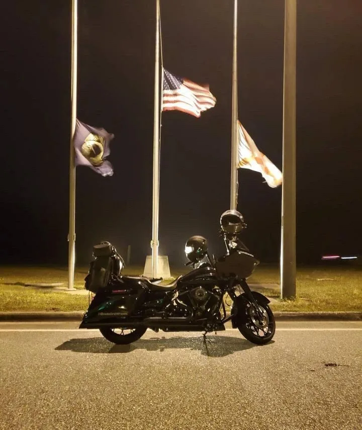 A motorcycle beside illuminated flags at night