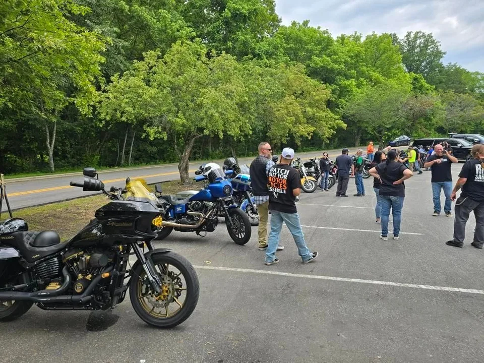 People gathered beside motorcycles, talking before a ride
