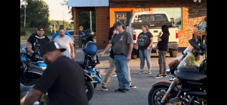 A group of people gathered with motorcycles outside a building