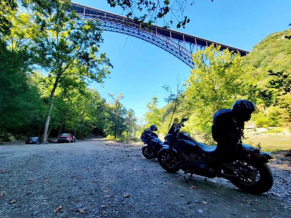Touring motorcycles below the New River Gorge Bridge beside the river